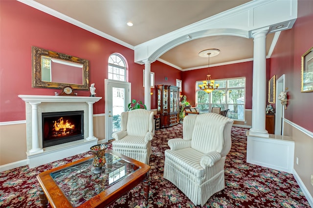 living area with ornate columns, a wealth of natural light, crown molding, and an inviting chandelier