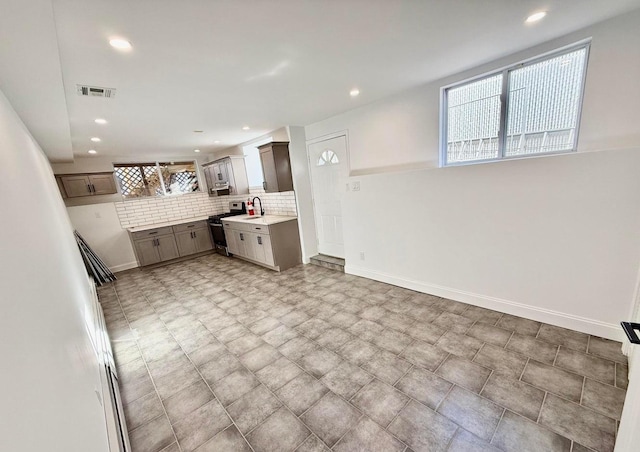 kitchen featuring sink, stainless steel gas range, and backsplash