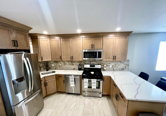 kitchen with a kitchen breakfast bar, stainless steel appliances, kitchen peninsula, light stone counters, and sink