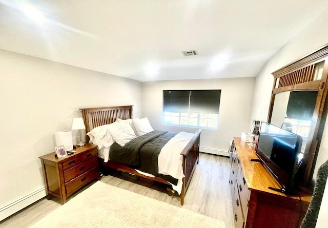 bedroom with a baseboard radiator and light hardwood / wood-style floors