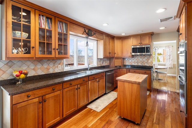 kitchen with butcher block counters, sink, a center island, stainless steel appliances, and light wood-type flooring