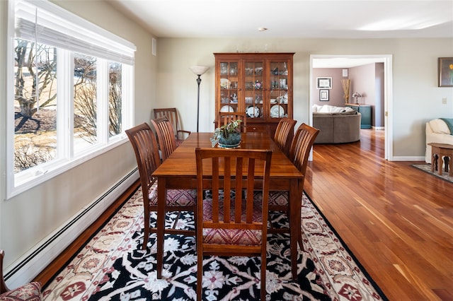 dining space with a baseboard heating unit and wood-type flooring