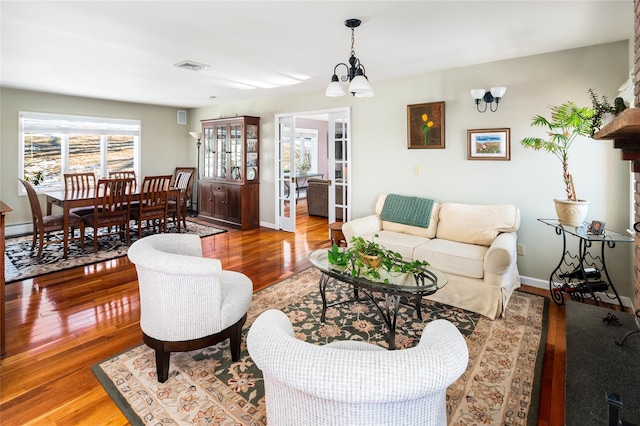 living room with a notable chandelier, wood-type flooring, and french doors