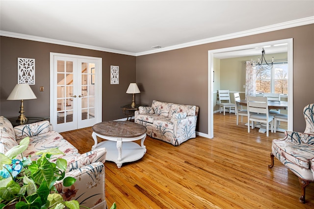 living room with crown molding, wood-type flooring, french doors, and a chandelier