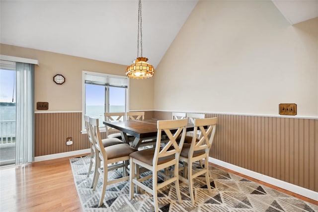 dining room with a notable chandelier, lofted ceiling, a water view, and light hardwood / wood-style floors