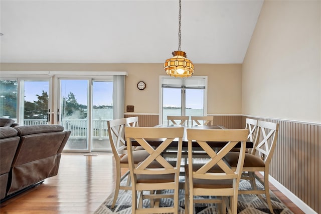 dining area with lofted ceiling, a water view, and light hardwood / wood-style floors