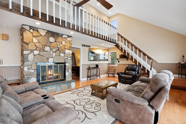 living room with high vaulted ceiling, wood-type flooring, and a stone fireplace