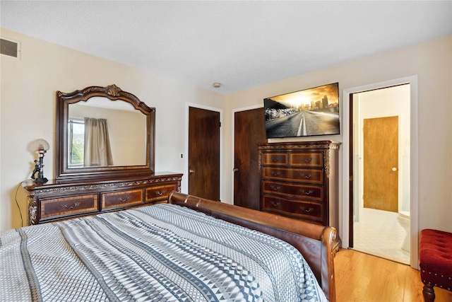 bedroom featuring ensuite bath and hardwood / wood-style floors