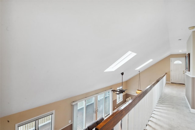 hallway with lofted ceiling with skylight and light carpet