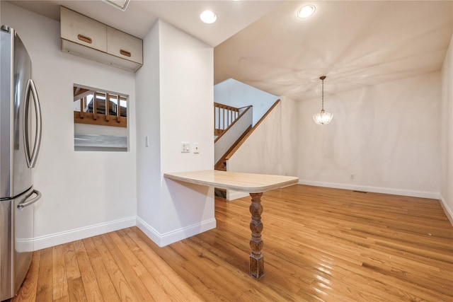 interior space with pendant lighting, stainless steel fridge, and light hardwood / wood-style flooring