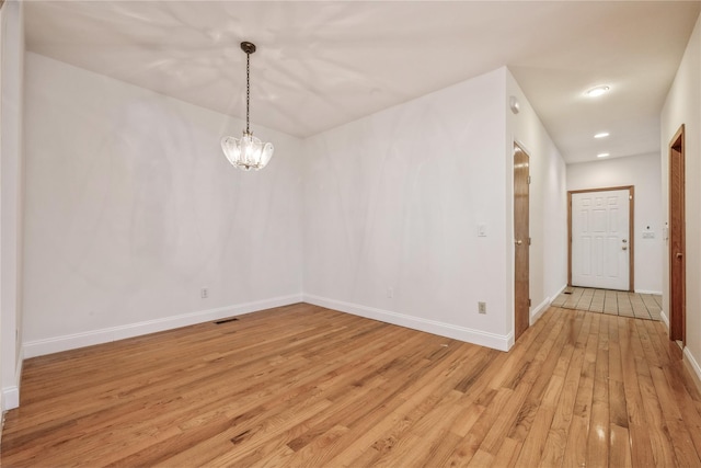 unfurnished room featuring light hardwood / wood-style floors and a notable chandelier