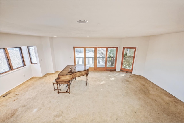 living area with a wealth of natural light, light carpet, and french doors