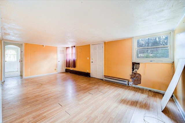 empty room featuring a baseboard heating unit, a textured ceiling, and light hardwood / wood-style flooring