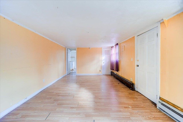 empty room featuring a baseboard heating unit and light wood-type flooring