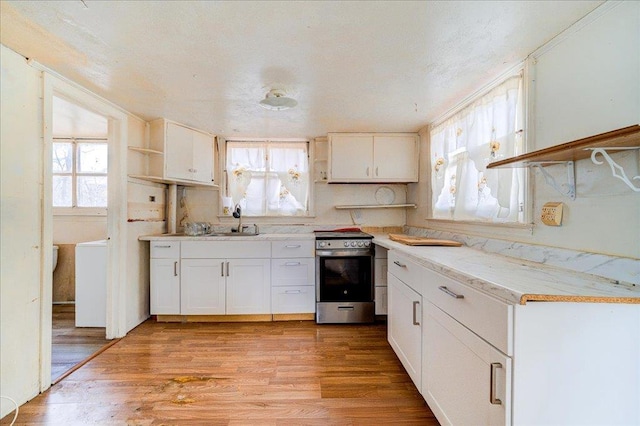 kitchen featuring stainless steel range with electric stovetop, white cabinets, light hardwood / wood-style flooring, and sink