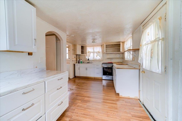 kitchen featuring stainless steel range, light hardwood / wood-style floors, white cabinets, and light stone countertops