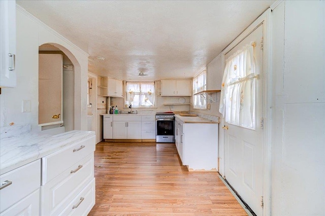 kitchen featuring sink, white cabinetry, light hardwood / wood-style flooring, light stone countertops, and stainless steel range with electric cooktop