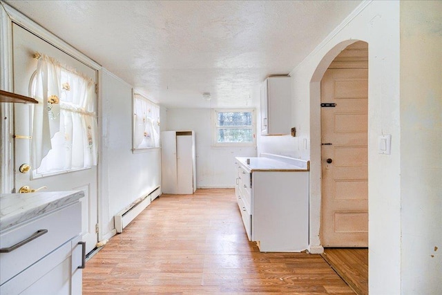 kitchen with a textured ceiling, baseboard heating, white cabinetry, and light hardwood / wood-style floors