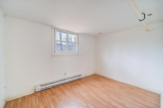 empty room featuring a baseboard heating unit and light hardwood / wood-style flooring