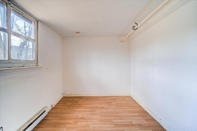 unfurnished room featuring light hardwood / wood-style floors and a baseboard heating unit