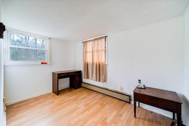 spare room featuring a baseboard heating unit and light hardwood / wood-style floors