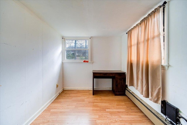 unfurnished room with a baseboard heating unit and light hardwood / wood-style flooring