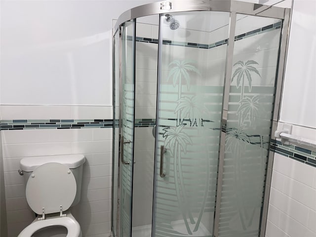 bathroom with tile walls, a shower with shower door, and toilet