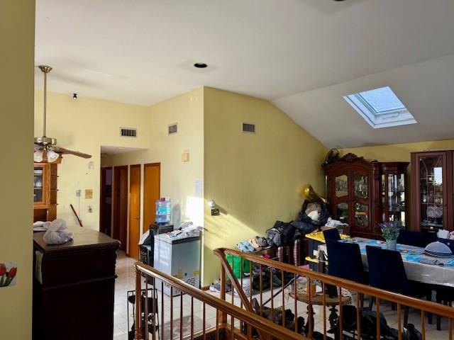 interior space with ceiling fan and vaulted ceiling with skylight