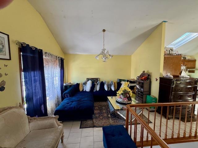 living room with light tile patterned floors, a notable chandelier, and vaulted ceiling