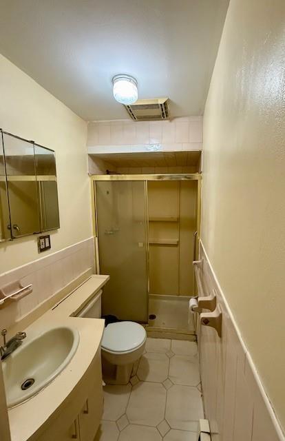 bathroom with tile patterned floors, walk in shower, vanity, and toilet