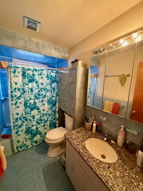 full bathroom with tasteful backsplash, vanity, toilet, and shower / bath combo with shower curtain