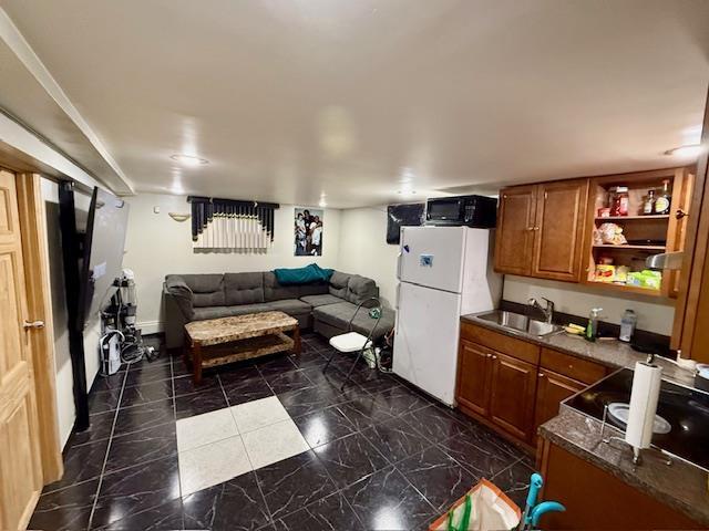 kitchen featuring sink, white refrigerator, and dark stone counters