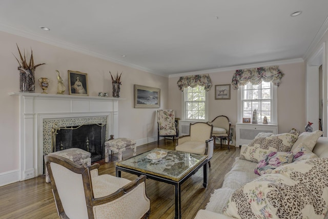 living room with a tiled fireplace, crown molding, and hardwood / wood-style flooring