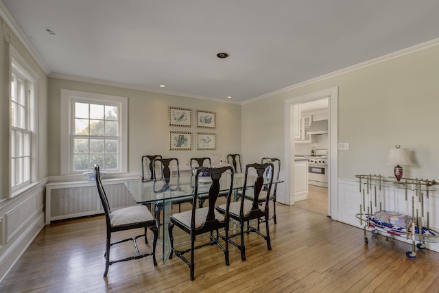 dining area with radiator heating unit, ornamental molding, and light wood-type flooring