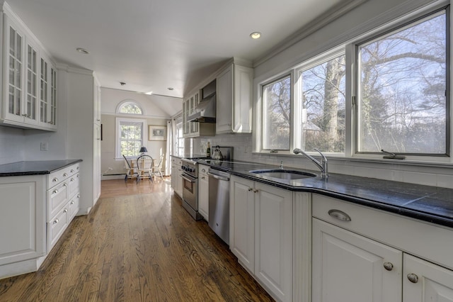 kitchen with dishwasher, white cabinetry, sink, wall oven, and wall chimney range hood