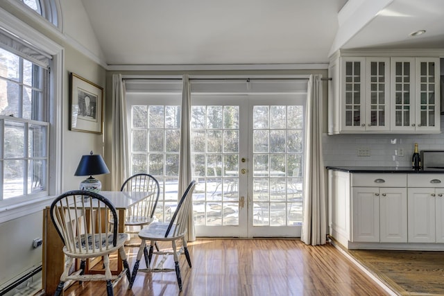 interior space featuring plenty of natural light, light hardwood / wood-style floors, vaulted ceiling, and baseboard heating