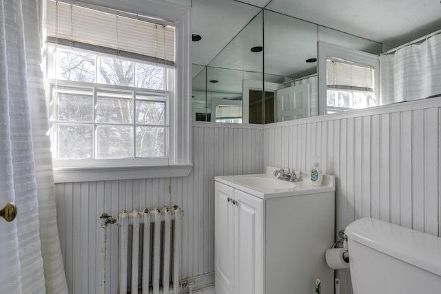 bathroom featuring vanity, radiator heating unit, and toilet