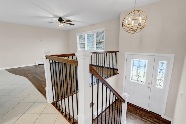 foyer featuring ceiling fan with notable chandelier, baseboard heating, and tile patterned floors