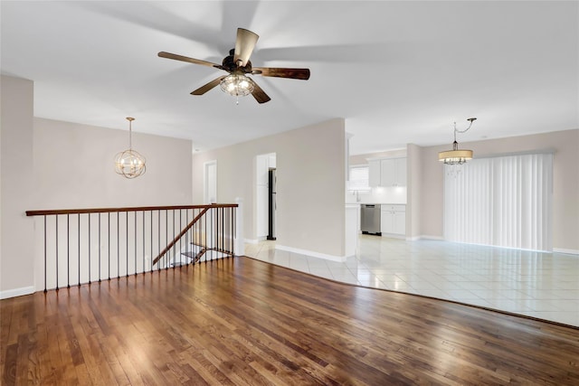 unfurnished room featuring ceiling fan with notable chandelier, sink, and light hardwood / wood-style flooring