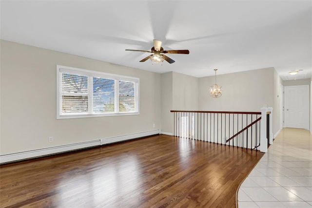 spare room with ceiling fan with notable chandelier, a baseboard radiator, and hardwood / wood-style floors