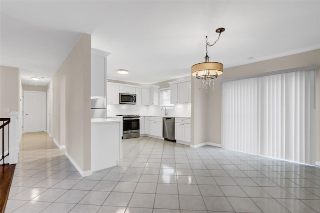 kitchen featuring pendant lighting, white cabinets, stainless steel appliances, an inviting chandelier, and light tile patterned floors