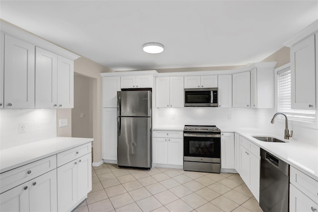 kitchen with sink, white cabinets, light tile patterned floors, and stainless steel appliances