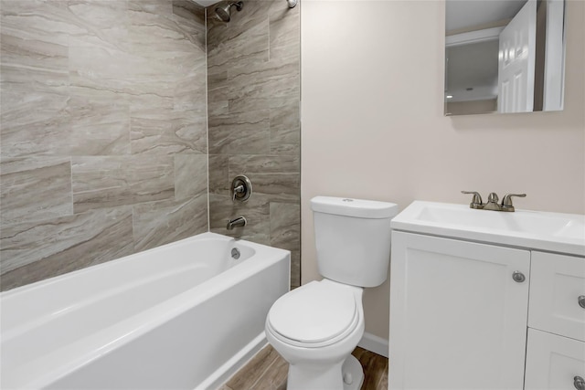 full bathroom featuring hardwood / wood-style floors, toilet, tiled shower / bath, and vanity