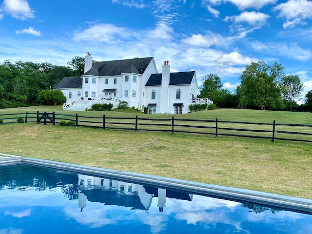 back of house featuring a rural view and a yard