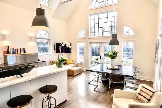 dining space with french doors, wood-type flooring, and a towering ceiling