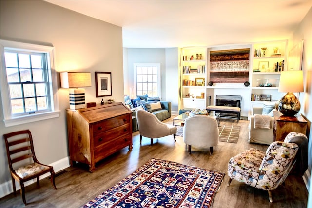 living area with wood-type flooring, plenty of natural light, built in shelves, and a fireplace