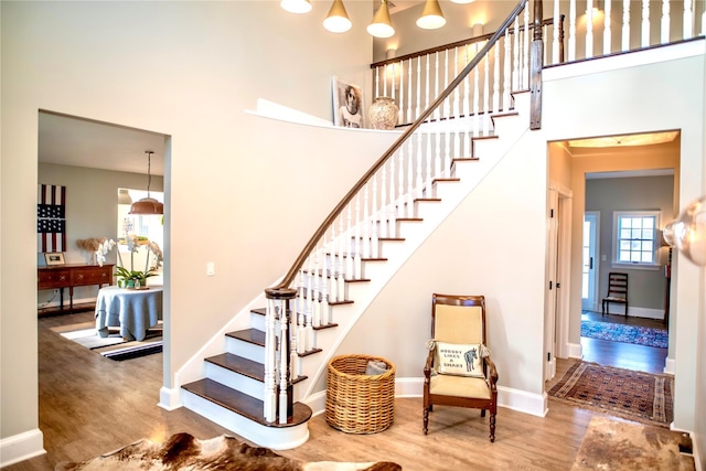 staircase with a high ceiling, baseboards, and wood finished floors