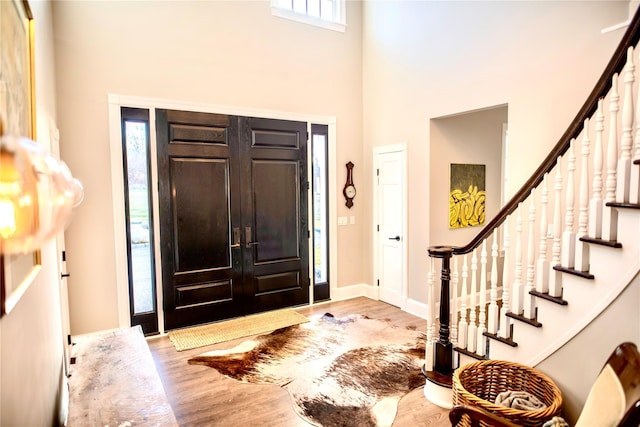 foyer with a high ceiling, plenty of natural light, and light wood-type flooring