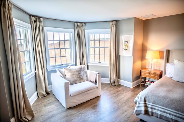 bedroom with visible vents, wood finished floors, and baseboards