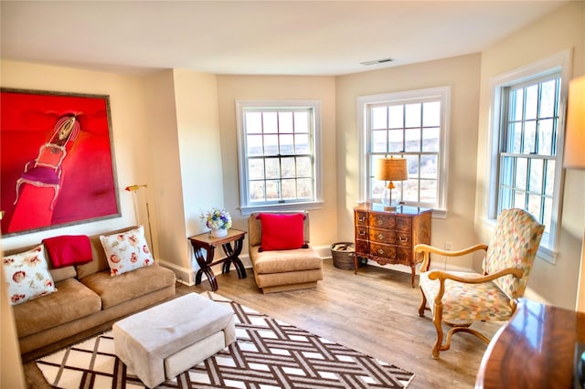 living area featuring a wealth of natural light, visible vents, baseboards, and wood finished floors